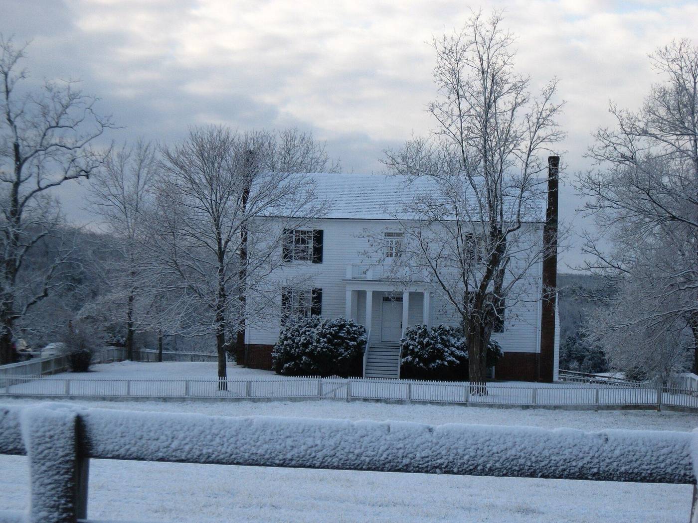 White colonial house in a snow-dusted yard